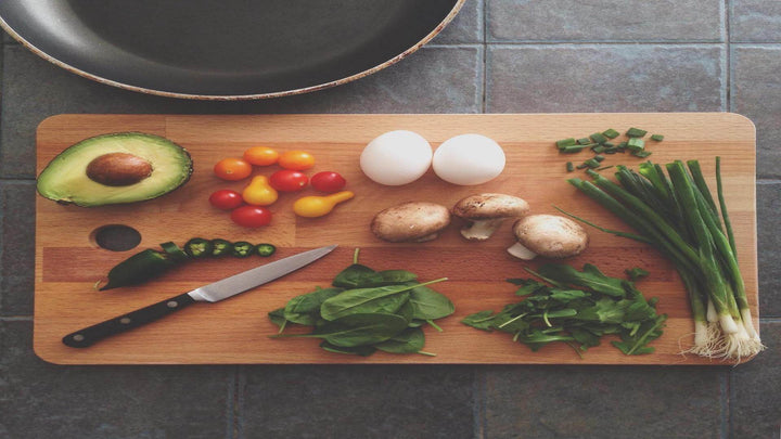 Photo of a frying pan and a wooden chopping board with various ingredients including eggs, mushrooms and spring onions, for e1011 Labs' page on cooking with hemp.