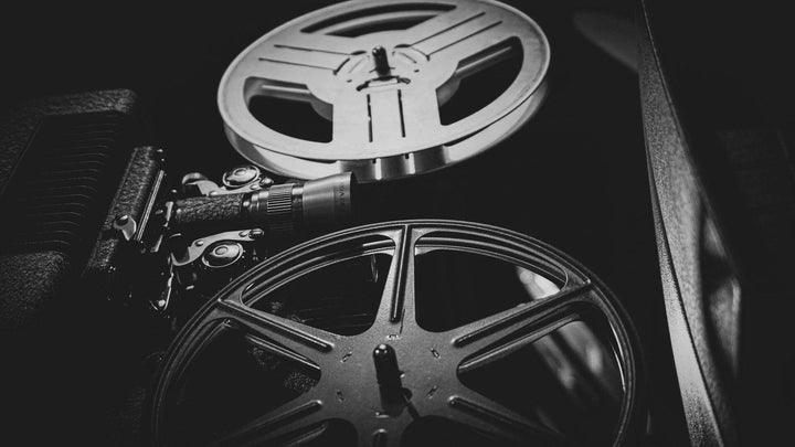 Closeup black and white photo of the reels of a cinema movie projector, for e1011 Labs' page on top 5 movies to watch while using their Elon & Stem products.
